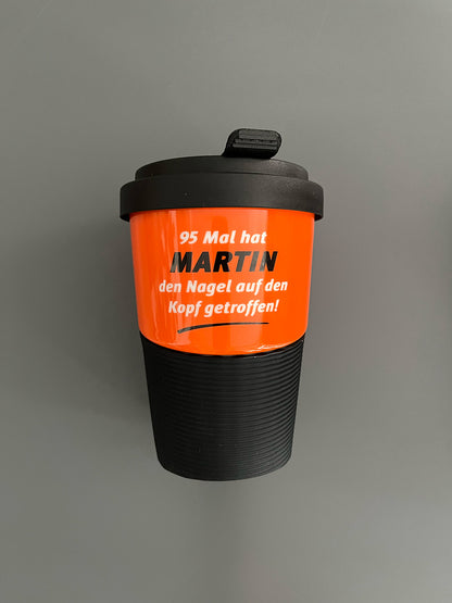 Kaffeebecher aus Porzellan in Orange mit dem Text "95 Mal hat Martin den Nagel auf den Kopf getroffen"