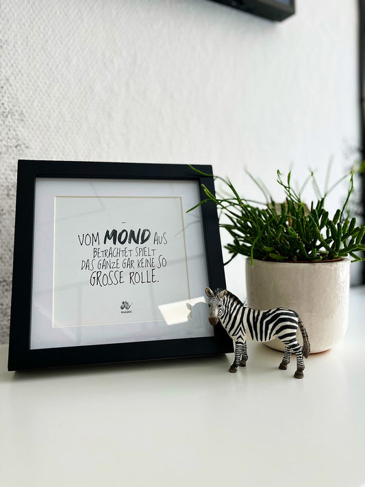 Weißes Bild von #heinzigartig mit Rahmen und dem Text "Vom Mond aus betrachtet, spielt das Ganze gar keine so große Rolle."
