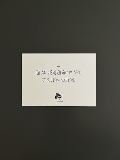 Weiße Postkarte von #heinzigartig mit dem Spruch: "Ich bin ziemlich gut im Bett. Ich fall kaum noch raus."