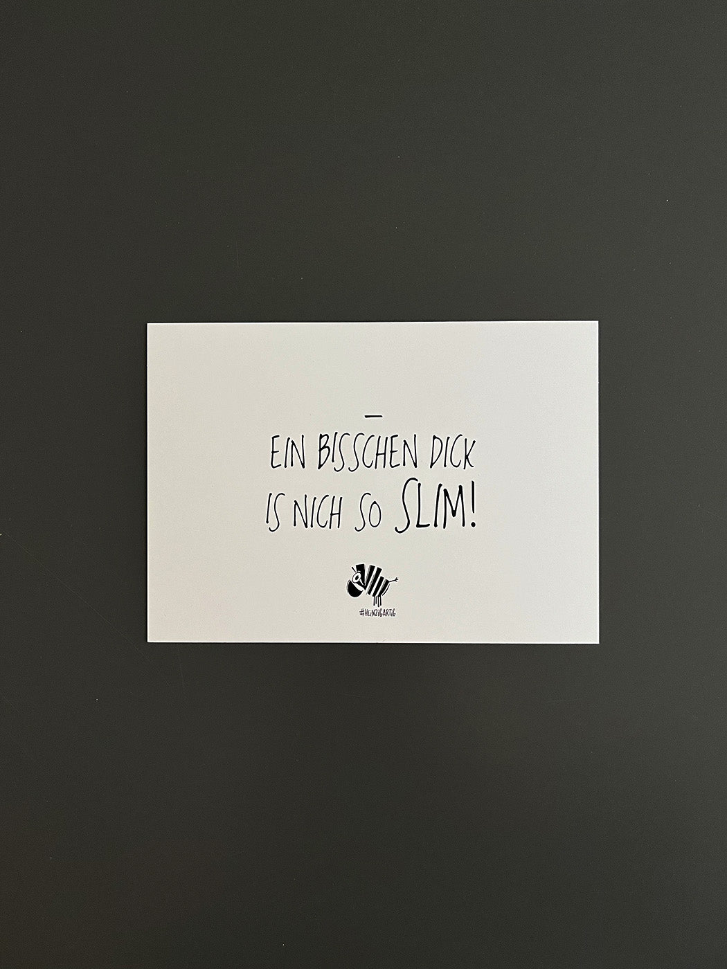 Weiße Postkarte von #heinzigartig mit dem Spruch: "Ein bisschen dick is nich so slim!"