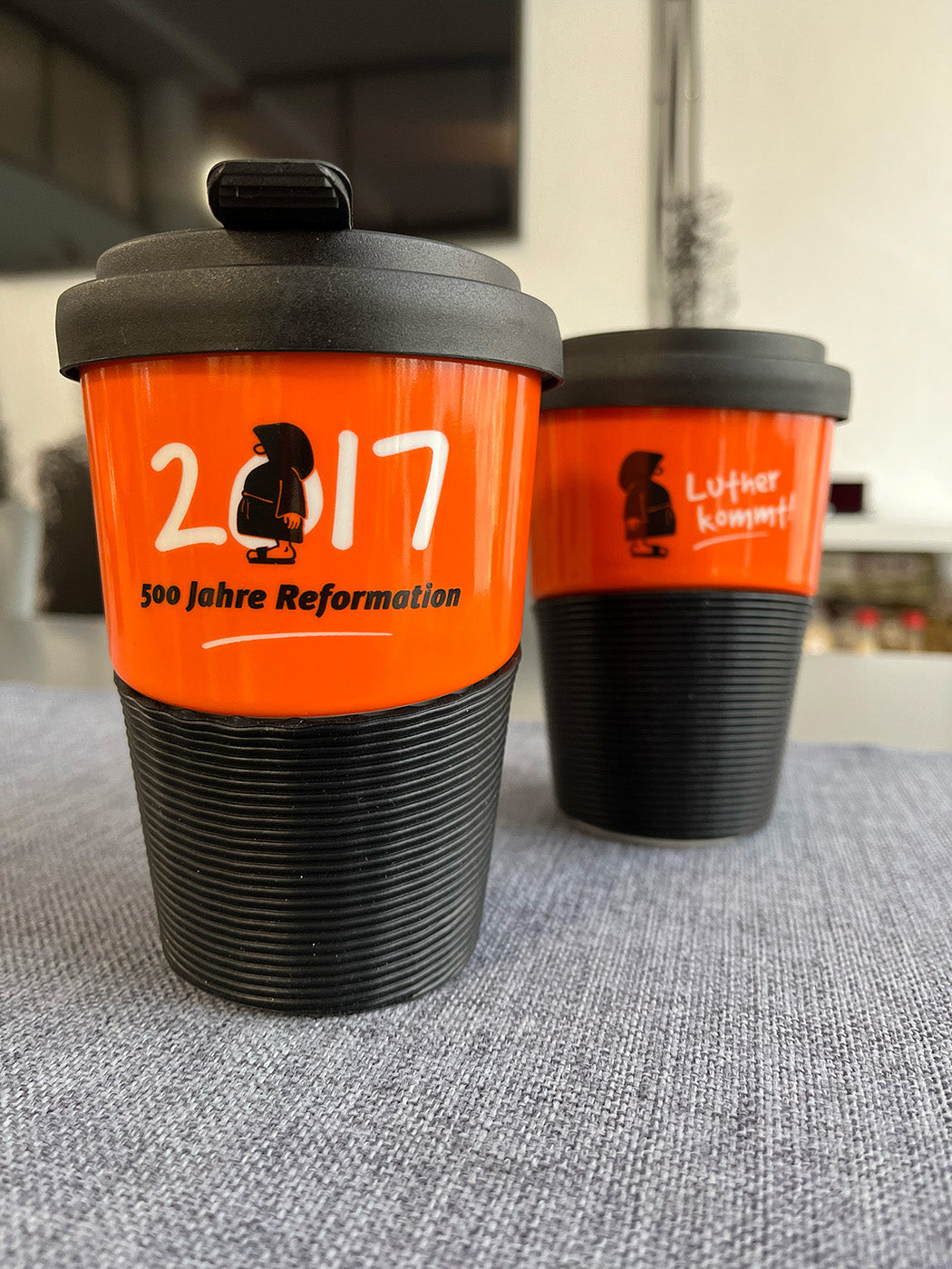 Kaffeebecher aus Porzellan in Orange mit dem Text "2017 - 500 Jahre Reformation"
