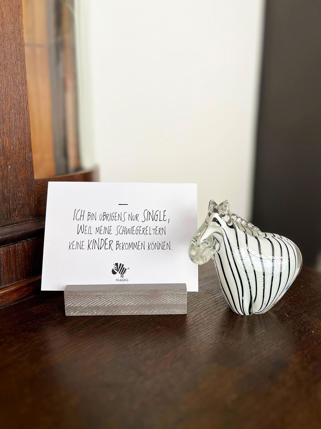 Weiße Postkarte von #heinzigartig mit dem Spruch: "Ich bin übrigens nur Single, weil meine Schwiegereltern keine Kinder bekommen können."