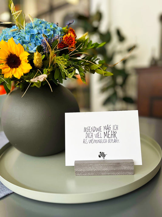 Weiße Postkarte von #heinzigartig mit dem Spruch: "Irgendwie mag ich dich viel mehr, als ursprünglich geplant"