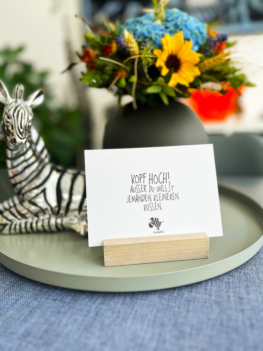 Weiße Postkarte von #heinzigartig mit dem Spruch: "Kopf hoch! Ausser du willst jemanden kleineren küssen."