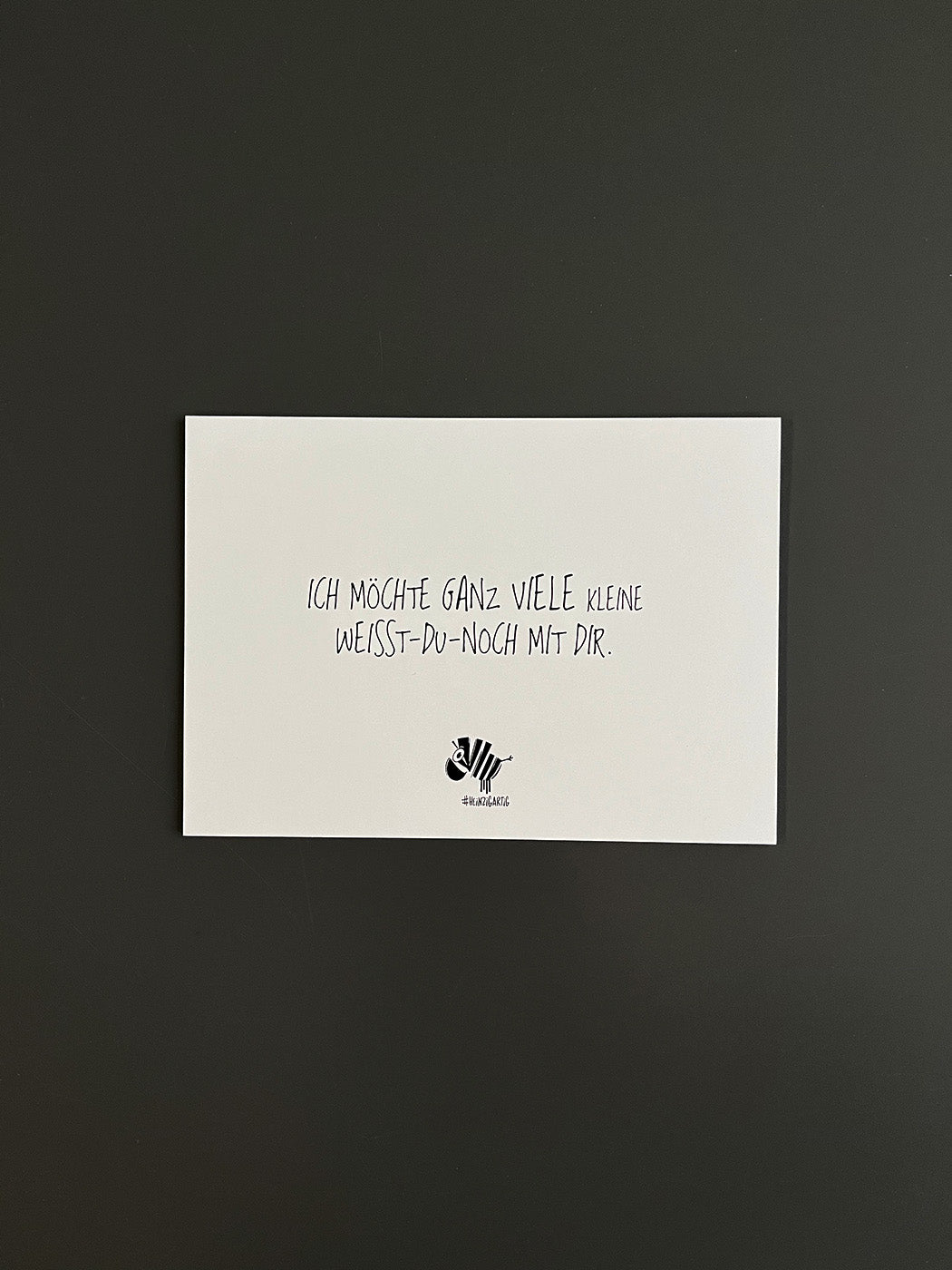 Weiße Postkarte von #heinzigartig mit dem Spruch: "Ich möchte ganz viele kleine Weisst-du-noch mit dir."