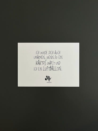 Weiße Postkarte von #heinzigartig mit dem Spruch: "Ich würde dich auch umarmen, wenn du ein Kaktus wärst und ich ein Luftballon."